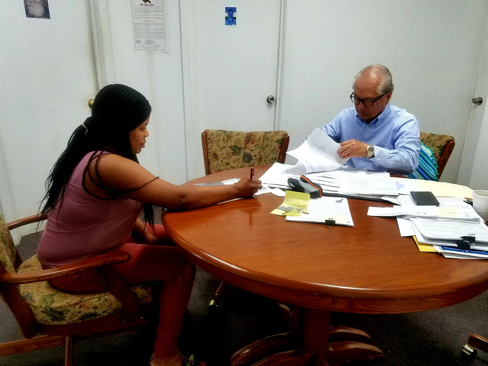 A staff member helping a visitor review paperwork at a table.